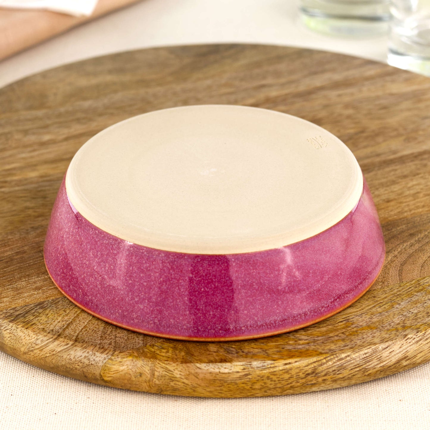 Base of a wheel-thrown Crimson tapas bowl, showing the smooth burnished foot and makers mark, handmade in a small Sussex pottery studio