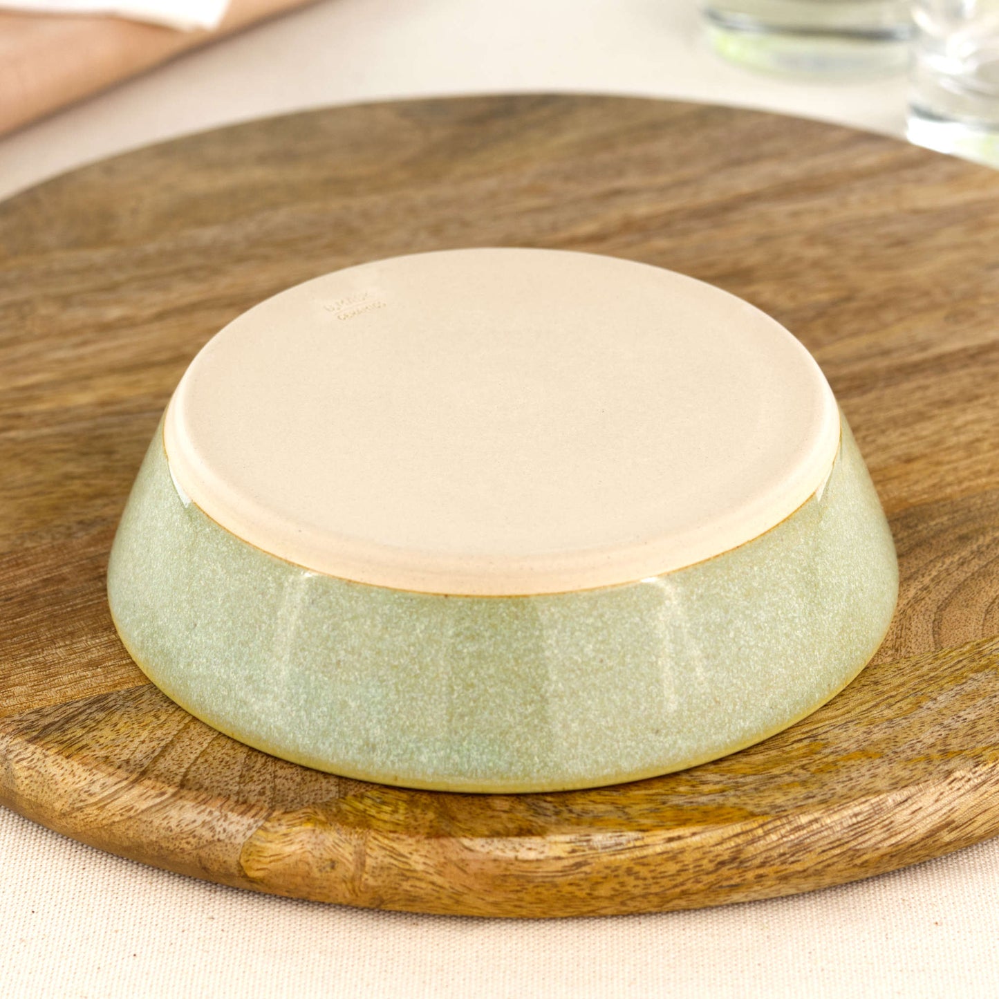 Base of a wheel-thrown Pale Green tapas bowl, showing the smooth burnished foot and makers mark, handmade in a small Sussex pottery studio