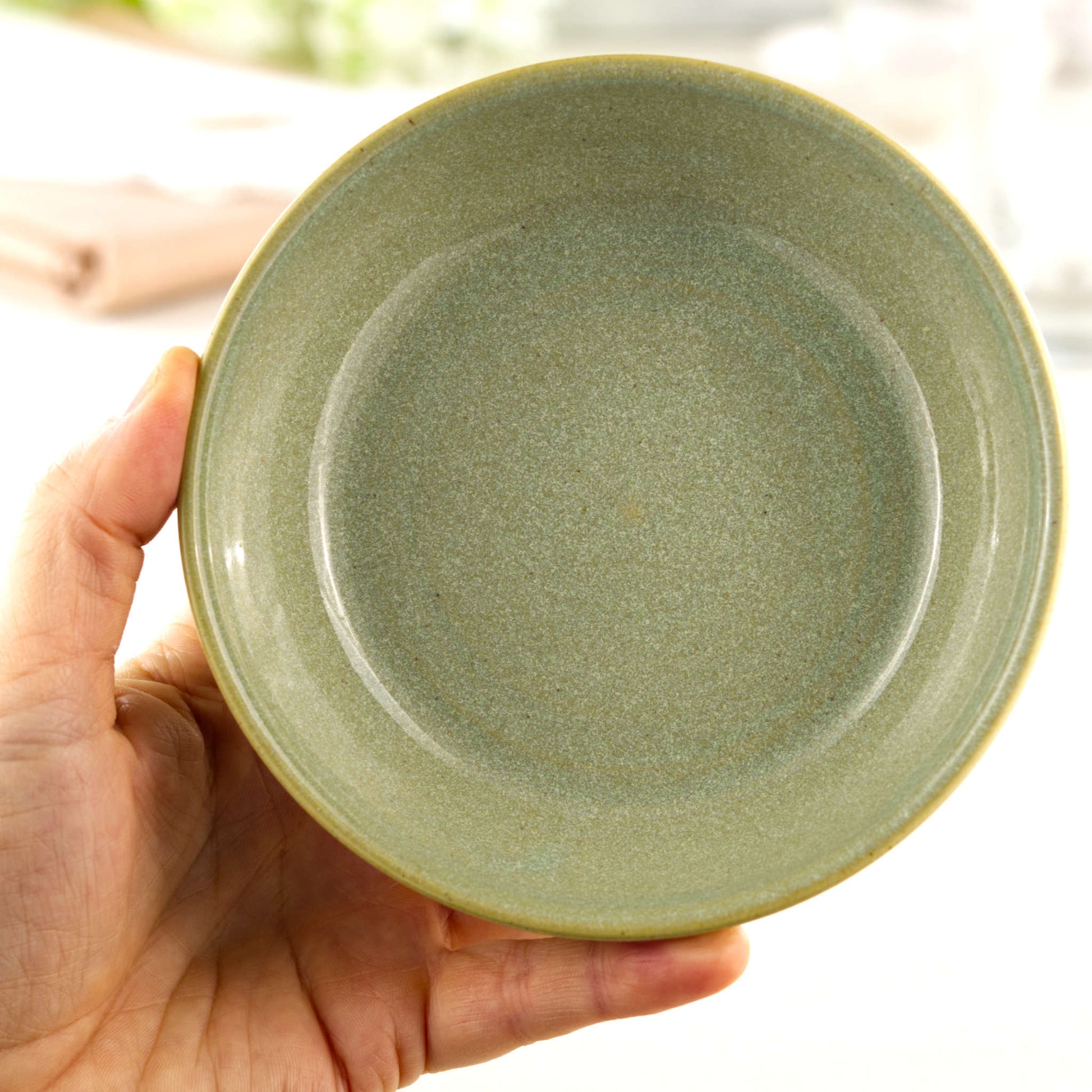 Handmade Pale Green ceramic tapas bowl held in the hand, a piece of British studio pottery sized for dips, mezze, side dishes and everyday nibble bowls