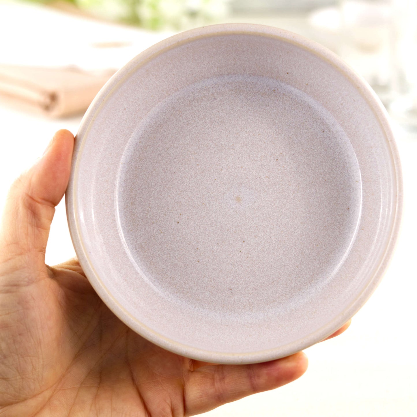 Handmade white ceramic tapas bowl held in the hand, a piece of British studio pottery sized for dips, olives, mezze and minimalist everyday serving